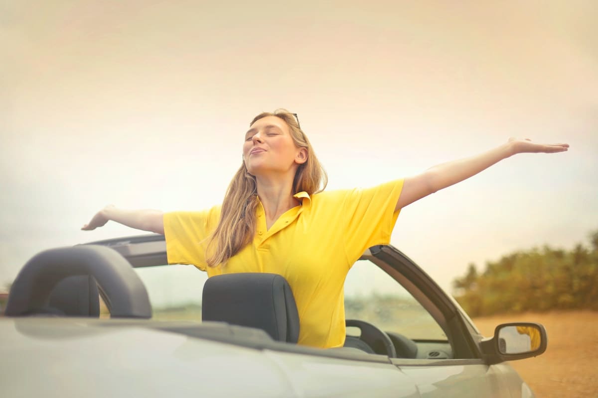 Lady rising her arms out of a convertible car