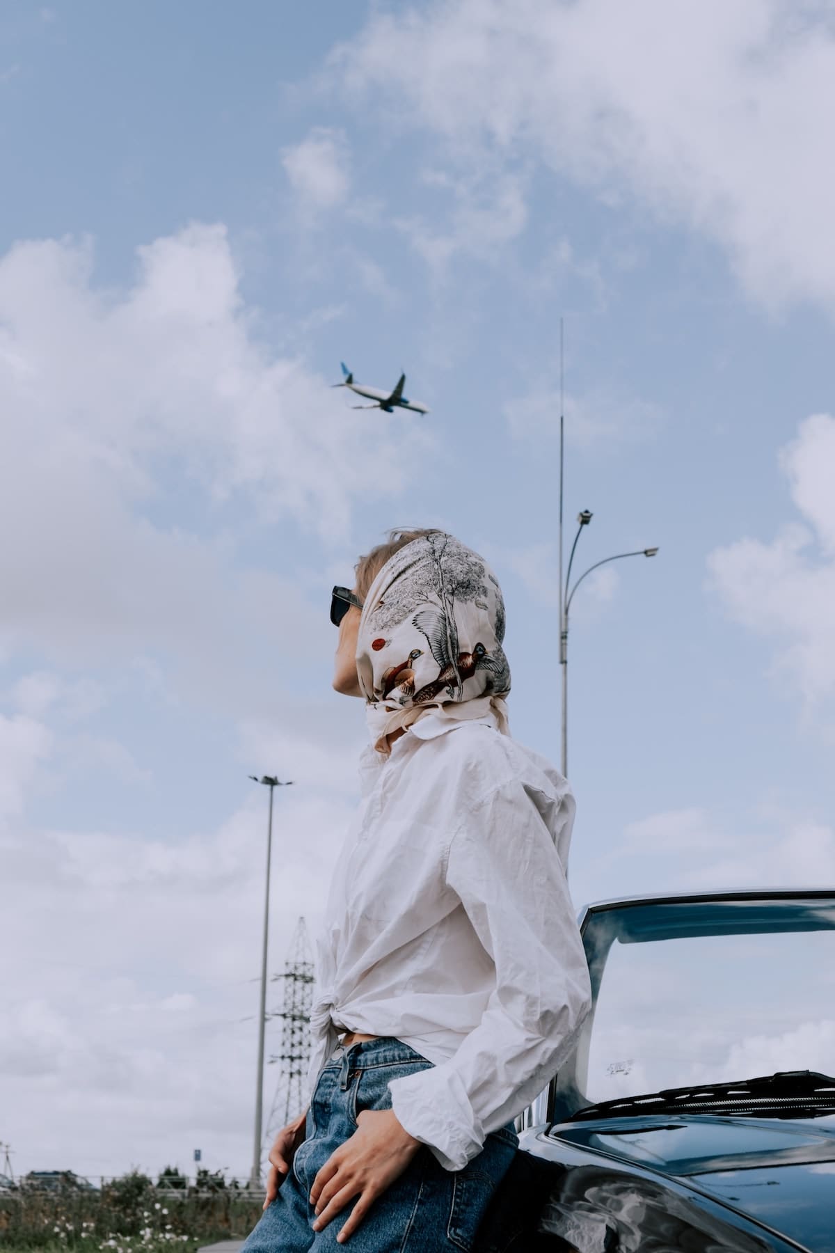 Lady stood by car looking up at Airplane
