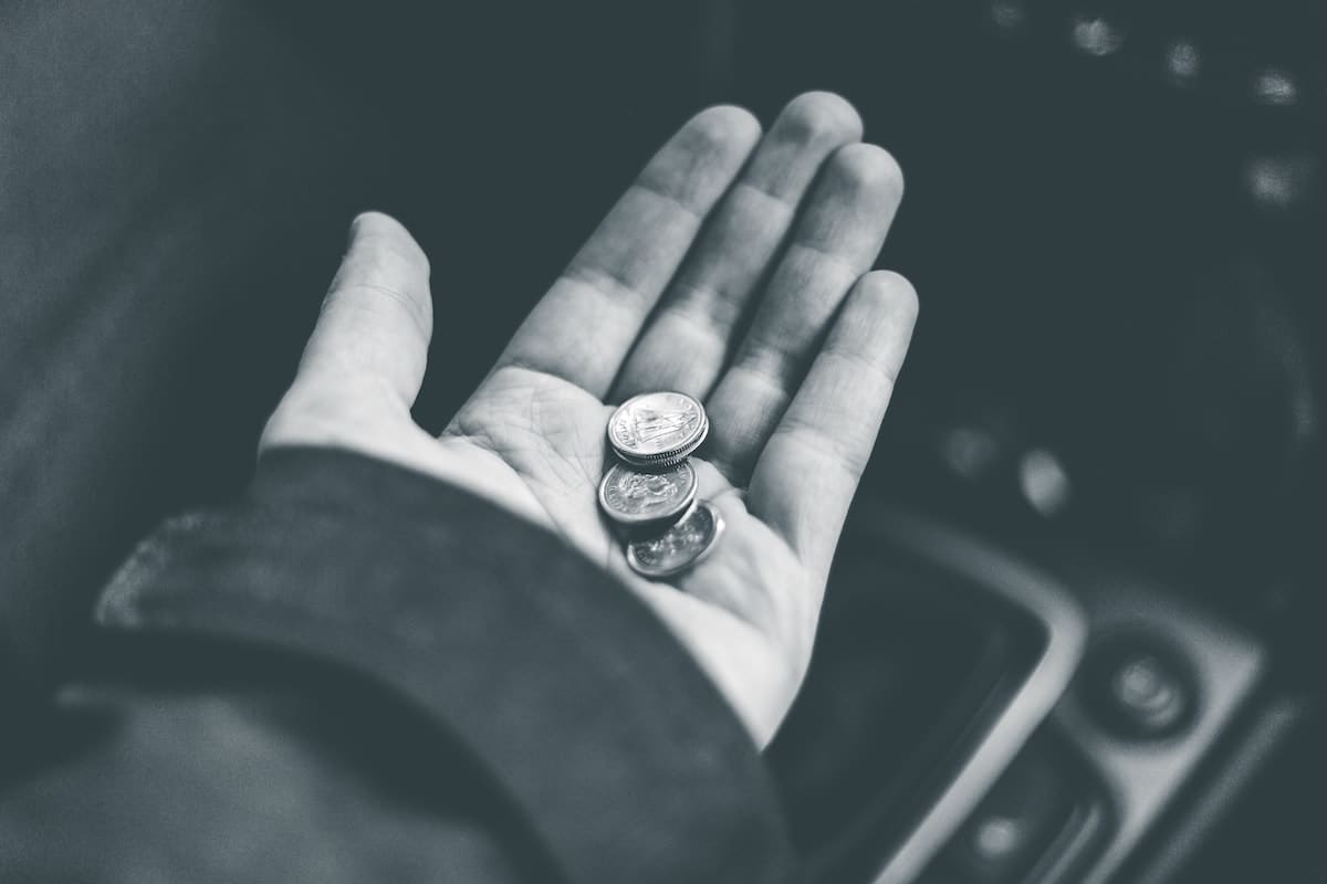 Photo of a hand with money placed in the palm, the person is sat in a car.