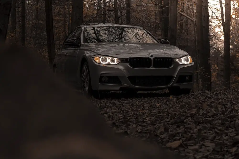 BMW parked up in the forest with its headlights on
