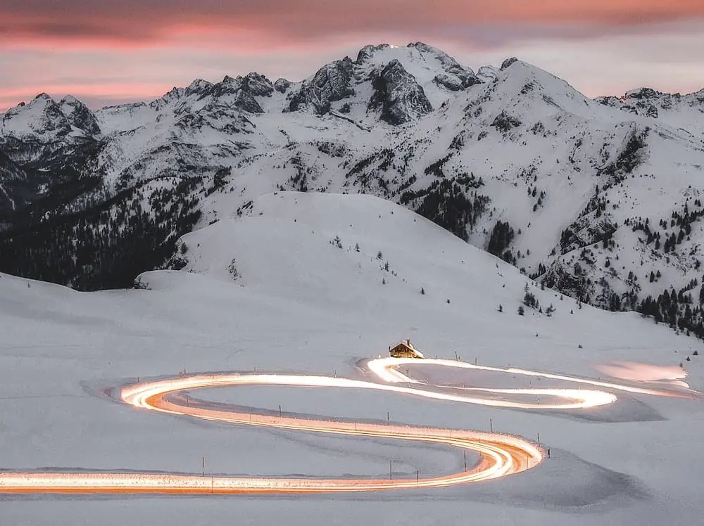 Winter mountain roads with car headlights streaming