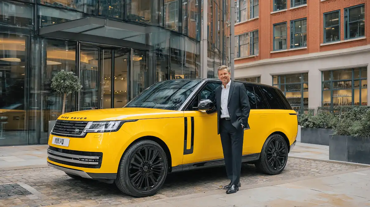 Company Director stood next to his Range Rover outside and office