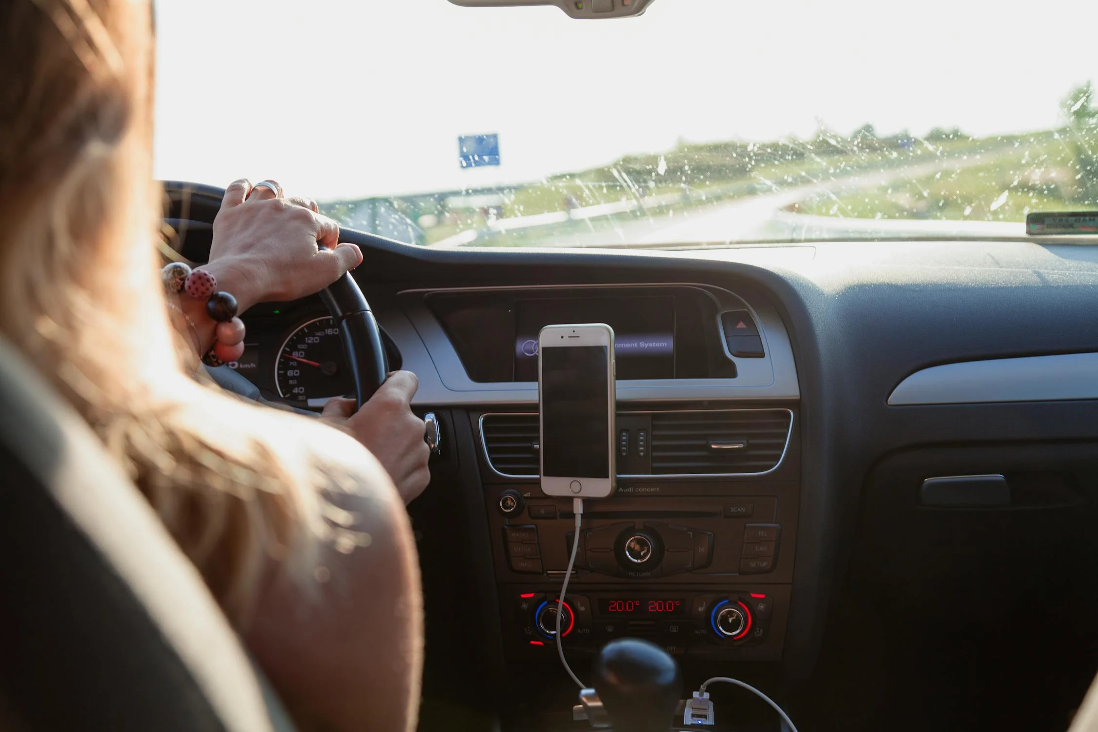 Person driving a car with an iPhone on a bracket